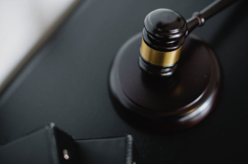 A black gavel rests on a judge's desk.
